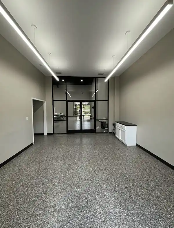 Long commercial corridor with glass doors and a flake epoxy floor
