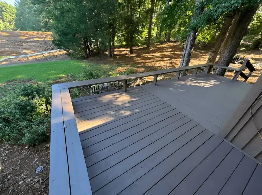 Gray-stained deck curving into a wooded yard