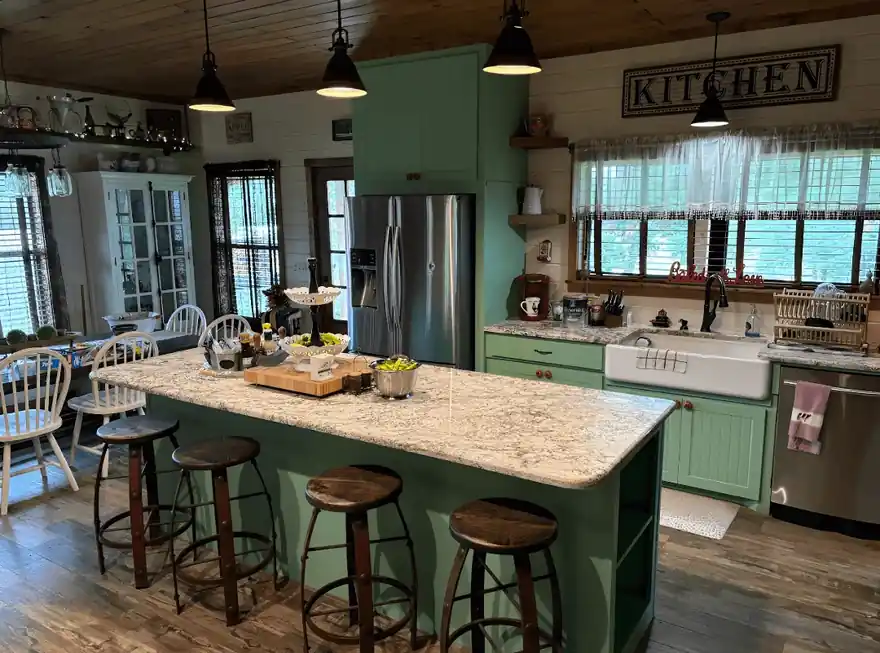 Farmhouse kitchen with sage-green painted island and perimeter cabinets