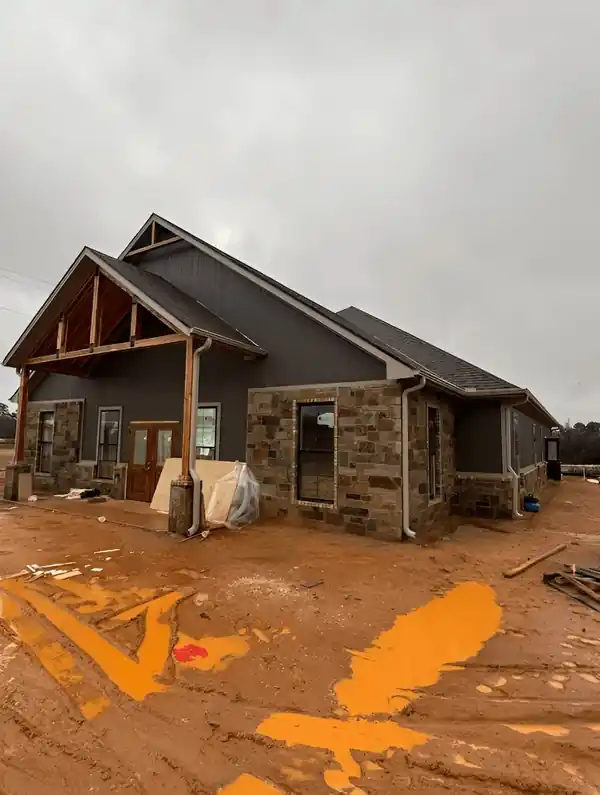 Stone and cream new-build house on red mud with stained gable timbers