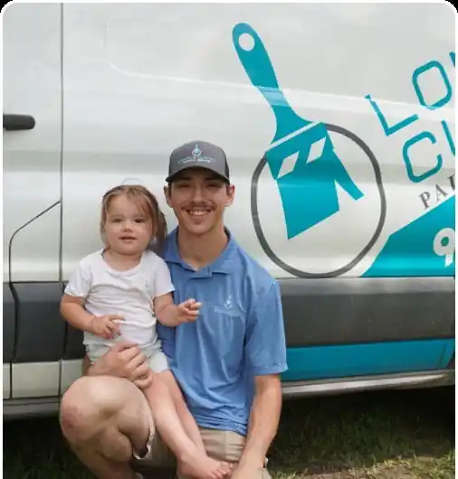A man crouching beside the white company van with a young child