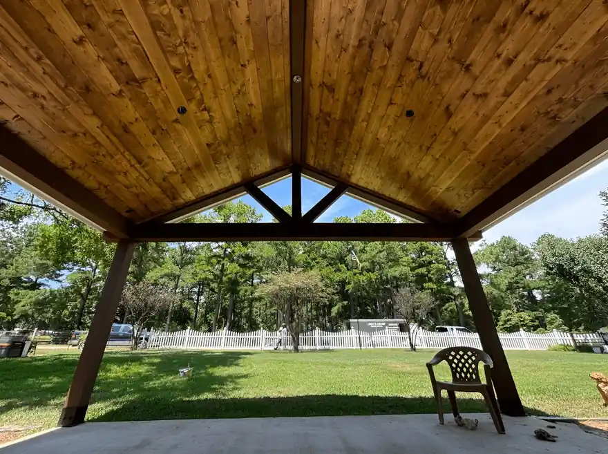 Stained cedar pavilion ceiling looking out to a white fence and pasture