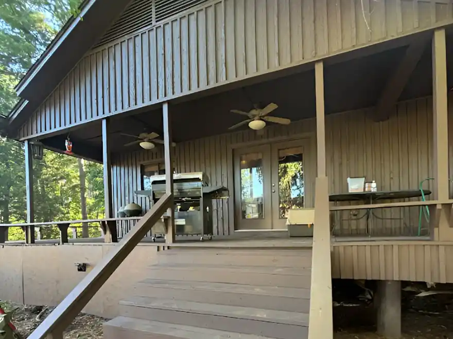 Stained porch deck and stairs on a board-and-batten home with ceiling fans overhead