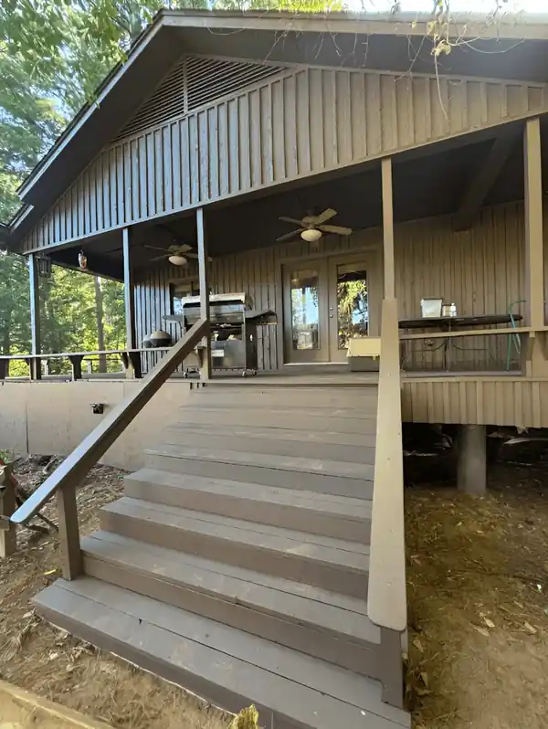 Stained wooden stairs up to a metal-roofed porch